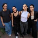 El flamenco volvió a respirar con acento contemporáneo en la Ciudad de México. El cuarteto español Las Migas aterrizó en la capital para presentar su más reciente disco, Flamencas, y confirmó que su vínculo con el público mexicano ya no es una promesa: es una realidad consolidada. “Esta vez ha sido muy especial”, cuentan tras su paso por el Centro Cultural Roberto Cantoral, donde ofrecieron un concierto que describen como “inolvidable”. No era su primera vez en el país —en 2018 tocaron en el Foro del Tejedor—, pero sí la confirmación de un crecimiento evidente. “He notado un público muy fan, un avance muy grande”, dicen. De la raíz a la reafirmación Con seis discos a cuestas, Las Migas sintieron la necesidad de volver al origen. Flamencas no es un gesto nostálgico, sino una reafirmación estética y política. “Queríamos volver a la raíz, al sitio de donde partimos, y enseñarle a la gente nuestra visión actual del flamenco”, explican. El proyecto dialoga directamente con sus dos álbumes anteriores: Libres y Rumberas. Las propias integrantes reconocen que estos tres trabajos conforman una especie de trilogía conceptual. Libres representó la apertura absoluta; Rumberas, una exploración rítmica que amplió su audiencia; y Flamencas, la consolidación de su identidad más tradicional, pero desde el presente. “Nosotras no sentimos que seamos un grupo de rumba, somos mucho más. Flamencas cierra esa trilogía volviendo al flamenco como declaración”, señalan. Flamenco y responsabilidad Hablar de flamenco en 2026 implica también revisar sus códigos. Las Migas asumen esa responsabilidad sin ambigüedades. “El flamenco tiene una parte tradicional muy potente, pero también arrastra letras y estructuras que hoy ya no nos representan”, reconocen. En ese terreno, su postura es clara: ocupar espacio. “Autodenominarnos flamencas hoy es una responsabilidad grande. Somos mujeres que queremos tener un lugar en ese mundo, llenar ese espacio para las nuevas generaciones”. No se trata únicamente de actualizar arreglos o modernizar la producción. Es una resignificación desde la interpretación, la narrativa y la presencia escénica. La tradición no se niega, pero se revisa. El directo como laboratorio Si el estudio es reflexión, el escenario es prueba. Y México fue el laboratorio perfecto. “Este disco estaba muy pensado para el directo. Es bastante auténtico, bastante cuarteto: lo que somos es lo que se ve en el escenario”. A diferencia de trabajos con mayor carga de producción, Flamencas se sostiene en la esencia instrumental y vocal del grupo. Eso ha permitido que el show fluya con naturalidad. Pero Las Migas no se conforman con “tocar canciones”: su apuesta actual es construir espectáculo. “Estamos muy centradas en el storytelling del show. No es solo ir tirando temas, es presentar un viaje”, explican. Para ello, sumaron a una escenógrafa externa que aportó mirada crítica. “Desde dentro puedes verlo hasta cierto punto. Una persona de fuera te dice: aquí muévete, aquí pasa esto detrás. Nos ayudó muchísimo”. La decisión evidencia una etapa de madurez artística: profesionalizar la puesta en escena sin perder espontaneidad. Una noche irrepetible El concierto en el Roberto Cantoral fue descrito por ellas mismas como “brutal”. Lo que más destacan no es solo la acústica del recinto o el público que las rodeaba —literalmente, con espectadores también detrás del escenario—, sino la sensación interna. “Hay veces que te subes a un escenario y pasan cosas que no puedes controlar. Este concierto no fue nada difícil. Estaba terminando y quería volver a empezarlo”. En primera fila, un grupo de superfans cantaba y bailaba cada tema. Ese intercambio emocional terminó de sellar la experiencia. “De estas cosas que no te puedes creer”, confiesan. México: inspiración y caos Más allá del escenario, la ciudad también dejó huella. Les sorprendieron los árboles antiguos, la vegetación exuberante y la intensidad cromática. El tráfico, admiten entre risas, “es algo a mejorar”. Pero la energía cultural compensó cualquier jet lag. El viaje, de hecho, fue una odisea estratégica para combatir el desfase horario. Intentaron regular el sueño en el avión; fracasaron. Llegaron prácticamente directas al teatro. “Esa noche la tenemos un poco borrosa, no sabemos si fue real o un sueño”. Aun así, la descarga emocional del concierto lo justificó todo. Un proyecto sin fronteras Las Migas no comparten ciudad. Viven entre Sevilla, Córdoba, Barcelona, Menorca y otros puntos. Esa dispersión complica los ensayos, pero eleva la intensidad de los encuentros. “Cuando nos vemos es trabajo intensísimo. No hay rutina de ensayo todos los miércoles. Es fiesta y creación concentrada”. La elección de integrantes nunca ha respondido a la geografía. “No puedes limitar el proyecto a una ciudad. Cuando hemos necesitado una nueva componente, hemos ido donde estuviera”. Esa apertura explica la diversidad de estímulos que nutre al grupo y su capacidad de reinventarse sin perder cohesión. Lo que viene Aunque el arranque de 2026 fue más lento de lo esperado, la gira ha ido tomando impulso. Noviembre contempla fechas en América, y México podría convertirse en parada obligada. “Esto se nos ha hecho muy corto. El teatro estaba lleno. Nos dijeron que había sido de lo más grande que había pasado ahí. ¿Por qué no dijeron que volverían?, nos preguntaron. Pues quizá lo estamos diciendo ahora”. Su deseo es claro: más días, más ciudades, una gira de teatros y, si es posible, colaboraciones con músicos locales, incluso con exponentes de son jarocho. El moodboard de una etapa Si tuvieran que definir esta fase con elementos visuales y conceptuales, la lista sería precisa: Claveles. Rojo, blanco y negro. Elegancia. Flamenco. Hermandad musical. Un manifiesto en cinco palabras. Las Migas regresaron a la raíz para proyectarse hacia el futuro. Y México, todo indica, será parte fundamental de ese trayecto.